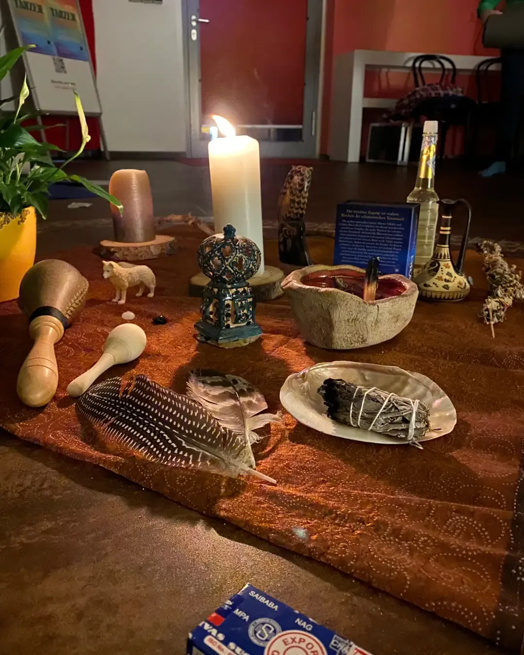 Ritualplatz mit Kerze, Federn, Trommelschlegel und Räucherwerk